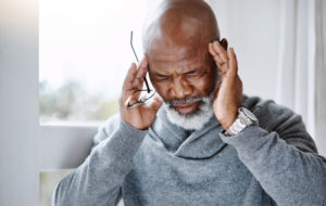 Shot of a handsome senior man suffering with a headache at home